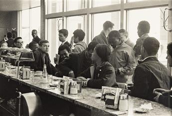 DANNY LYON (1942- ) SNCC Staff Sit-In, Atlanta, John Lewis behind Mendy Samstein (+ the pastries), Stokely Carmichael standing at right